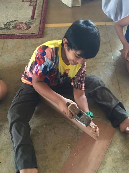 A young builder using a hand planer to shape a piece of wood. We teach basic woodworking skills, fostering a sense of accomplishment and confidence.