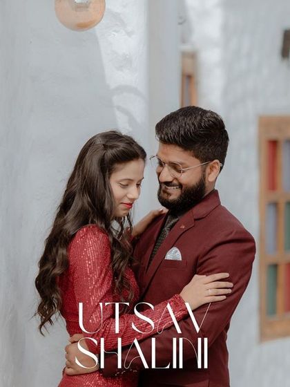 A close, loving embrace against a white, textured wall. The contrast of their red outfits and the simple background makes their connection the central focus.