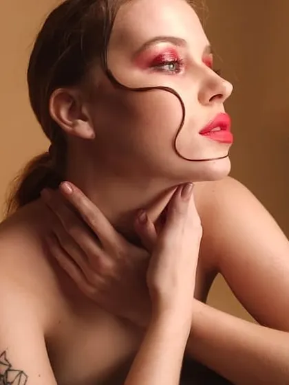 Another angle of the creative beauty look with red eyeshadow and a bold lip. This shot highlights the clean lines and precise application required for high-impact editorial makeup.