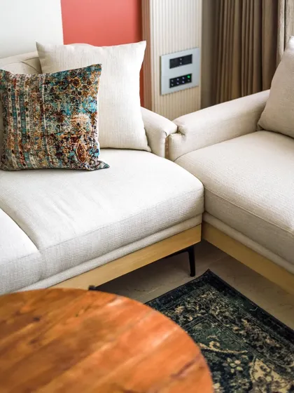 The living room features a neutral color palette with pops of color from the cushions and decor. The space is calm, interesting, and uncluttered.