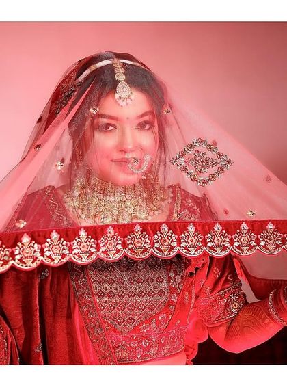 A lovely bridal portrait where the bride holds her veil, smiling directly at the camera, showcasing her joy.