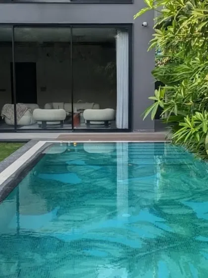 A view from the lawn towards the living space, where large glass doors blur the line between inside and out. This seamless connection to the garden and pool is a signature feature of our luxury villa designs.