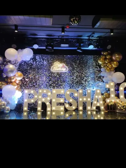 A glamorous stage for a 10th birthday, featuring large marquee letters spelling out "PRESHA 10" against a shimmering silver backdrop.