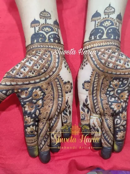 A traditional yet fancy design featuring royal elephants under umbrellas at the wrist. The palms have a bold, modern pattern with floral and geometric elements.