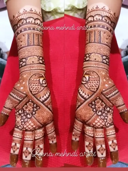A classic bridal design featuring prominent peacock figures. The pattern uses a mix of delicate lines and bold shapes to create a balanced and eye-catching look that extends up the arm.