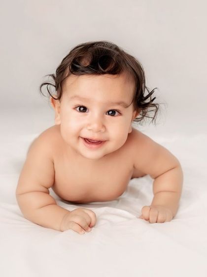 A classic "tummy time" shot for a baby who can hold their head up. A simple white background keeps the focus on the baby.