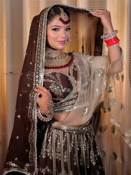 A full-length portrait showing the bride adjusting her dupatta, highlighting the shimmer of the sequined outfit.