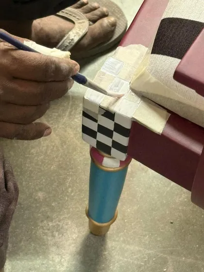 The soul of my work is in the handcrafted details. Here, an artisan meticulously hand-paints the checkerboard pattern on the leg of our chess-inspired bench, using traditional techniques to ensure sharp lines and rich character.