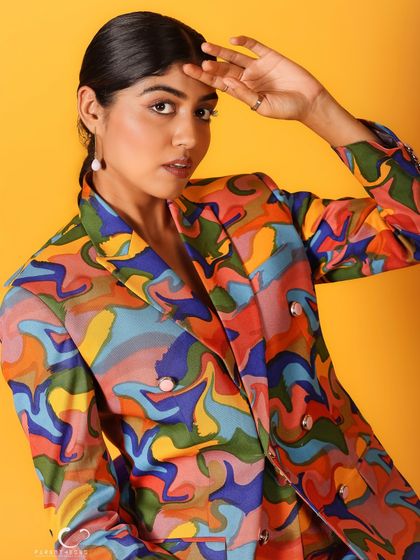 A high-fashion pose with a hand to the forehead. The composition is clean and impactful, letting the bold colors tell the story.