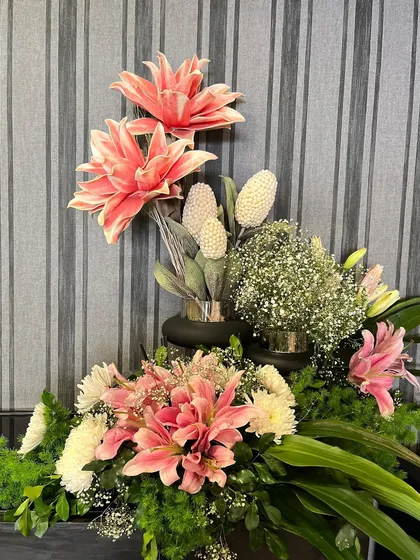 Even a small corner can be transformed with the right floral arrangement. This piece combines large pink dahlias with delicate baby's breath and greenery to add a touch of elegance and color to the space.
