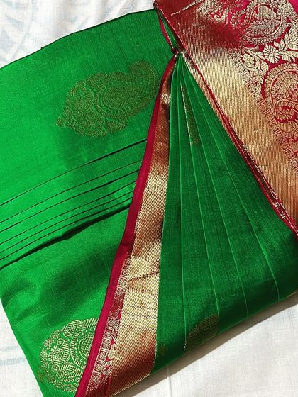 A vibrant green silk saree with a red and gold border. This classic piece is now ready for any traditional function.