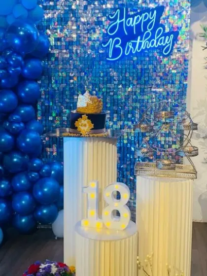 An 18th birthday celebration with a royal blue theme. The blue shimmer wall, matching balloon garland, and custom cakes create a cohesive and striking look for this important milestone.