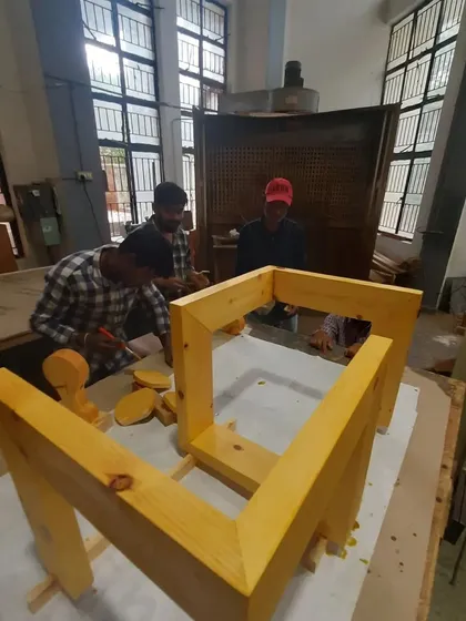Students work on the finishing stages of a solid wood project, applying coats and sanding between them.