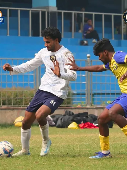 A player skillfully protects the ball from an opponent, showing great balance and control.