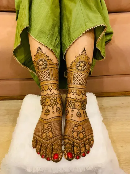 A complete bridal look includes detailed foot mehandi. This design features symmetrical patterns with fine lines and traditional motifs that extend from the toes to the ankles, perfectly complementing the hand designs.