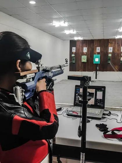 A shooter takes aim at the electronic target system during a practice session. The immediate feedback from the laptop allows for real time analysis and improvement.