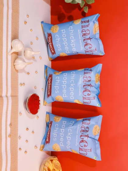 A top-down shot of barbecue flavored chips with ingredients like garlic and chili powder. The red and white background provides a nice contrast.