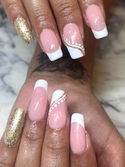 A classic French manicure with a touch of gold. This set features clean white tips on a square nail, with gold glitter accent nails and delicate gold and white dot detailing.