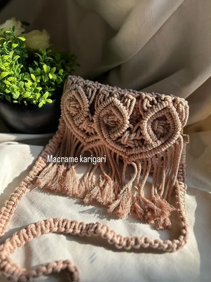 A full view of our macramé owl sling bag, showing the strap and fringe detail. This bag is handmade with intricate knots to create the owl design, making it a truly unique accessory.