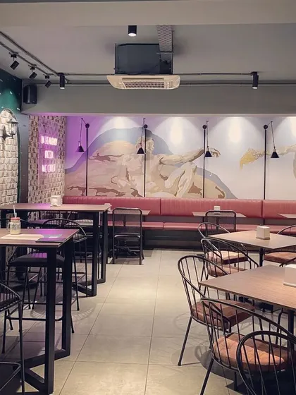 The interior of Raffaele's Pizzeria, where we embraced a rustic and raw design language. This view highlights the interplay of exposed brick, a large-scale hand-painted wall mural, and industrial-style seating that together create an authentic and cozy atmosphere.