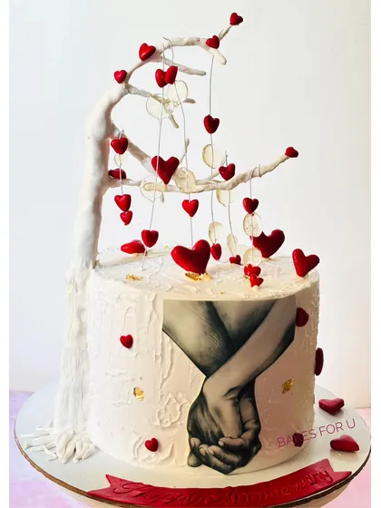 A romantic anniversary cake featuring a hand-painted portrait and a beautiful tree with hanging hearts. This design tells a love story and is perfect for celebrating a special connection.