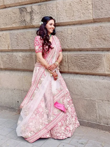 A full-length view of this bride's stunning pink floral lehenga. The soft makeup and hair allow her natural beauty and the intricate outfit to shine.