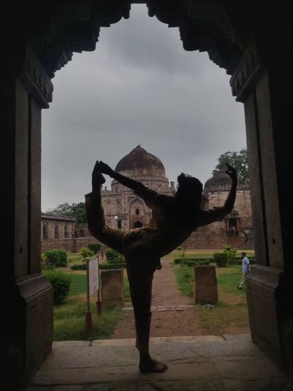 A silhouette of Natarajasana, the Lord of the Dance pose, framed by a historic archway. Yoga allows you to find beauty and expression in every shape.