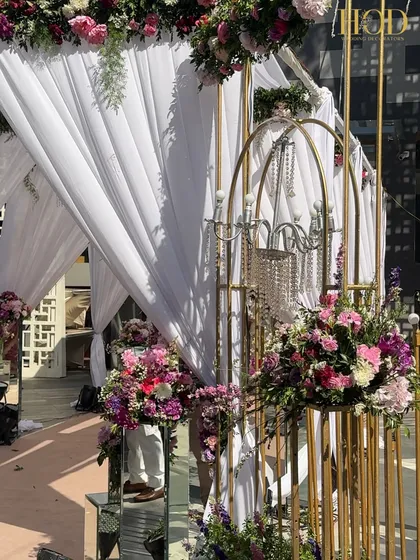 Another detail of the entrance, showing the combination of golden structures, chandeliers, and lush floral arrangements on mirrored pedestals.