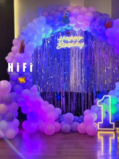 A Frozen-themed first birthday with a purple and blue balloon circle and a shimmering backdrop.