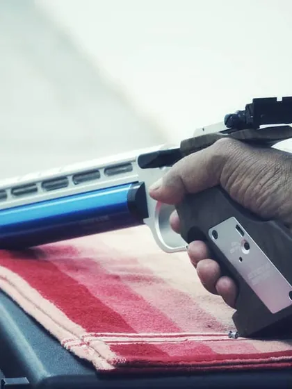 A shooter's hand gripping a 10m air pistol. The custom anatomical grip ensures a consistent and firm hold, which is vital for stability and shot control.