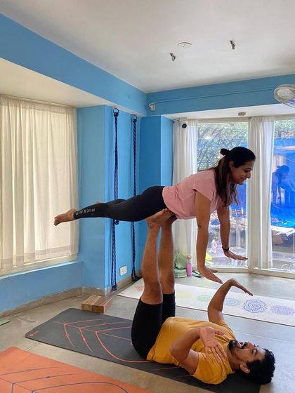 Demonstrating a basic Acro Yoga pose, 'Front Bird'. This pose helps build trust and stability for both the base and the flyer.