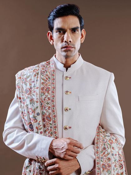 A close-up on a classic bandhgala-style sherwani, accented with a beautifully embroidered pashmina shawl. This look is perfect for a sophisticated winter wedding, combining warmth and impeccable style.