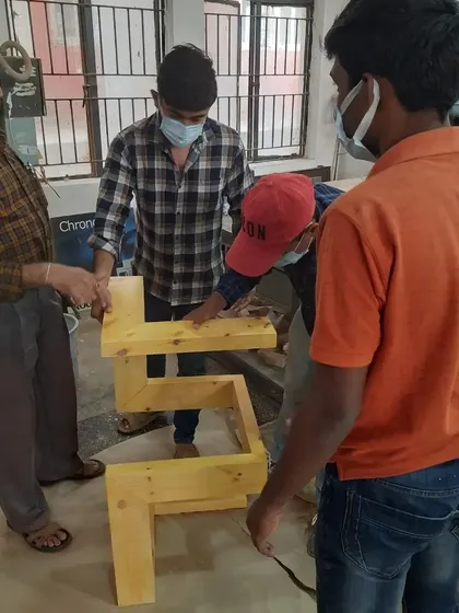 Our chief trainer assists students with the assembly of a complex, interlocking table base, ensuring the structure is sound.