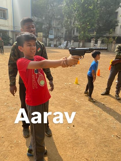 Aarav gets some helpful guidance from an instructor to perfect his aim and grip.
