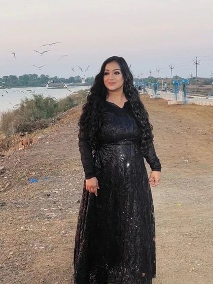 On location for a shoot with a model. The dramatic black outfit is paired with long, flowing curls and smokey eye makeup.