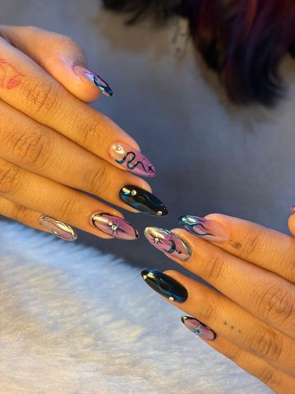 A full look at our iconic chrome nail art. This set features a mix of celestial designs, snakes, and flames, all created with a stunning metallic finish over a purple and black base.