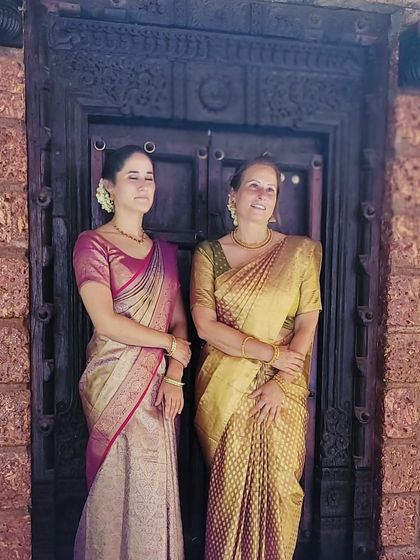 Another pose from the mother and daughter, showcasing their elegant drapes against a traditional Indian doorway.