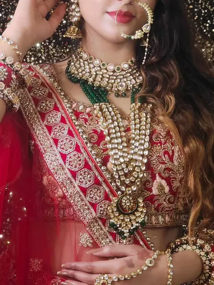 A close-up of a bride wearing a heavy, layered Kundan set with red and white stones. The intricate details of the hathphool are also visible.