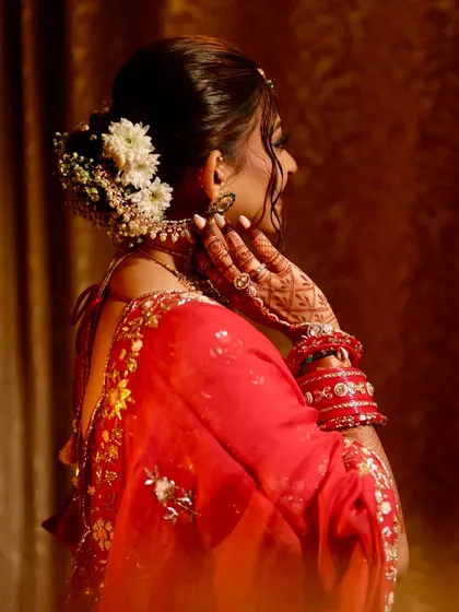 A view of the bride's back, showcasing her beautiful floral hair bun and the design of her blouse.