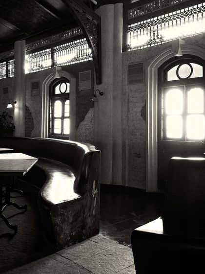 Sunlight streams through the large windows, highlighting the texture of the stone floor and the custom-built, wave-like bench.