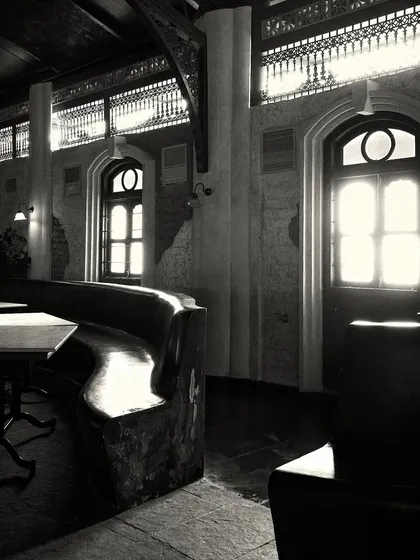 Sunlight streams through the large windows, highlighting the texture of the stone floor and the custom-built, wave-like bench.