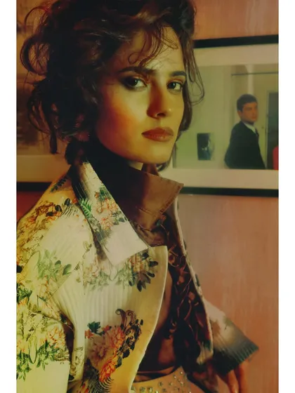 A portrait from 'Collision of Thens'. The model's direct gaze and the sophisticated styling of the patterned jacket show a character who is becoming more self-aware.