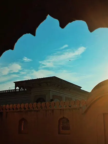 The sun sets behind a temple in Pushkar, viewed through an arched window. The silhouette and the burst of light create a beautiful frame, inviting you to pause and appreciate the moment.
