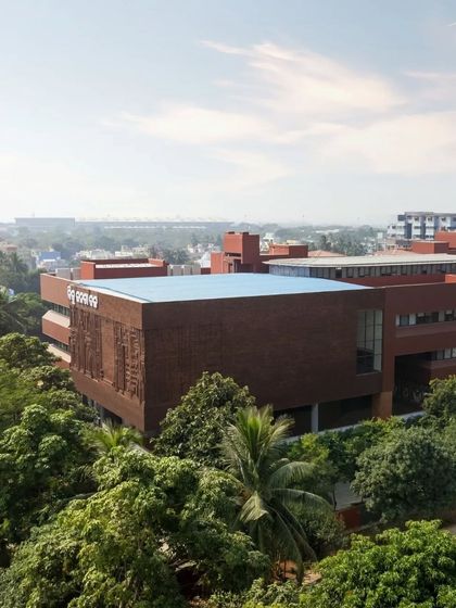An aerial view shows the BJD headquarters nestled amongst the trees, with its prominent brick-red volumes making a statement in the urban landscape.