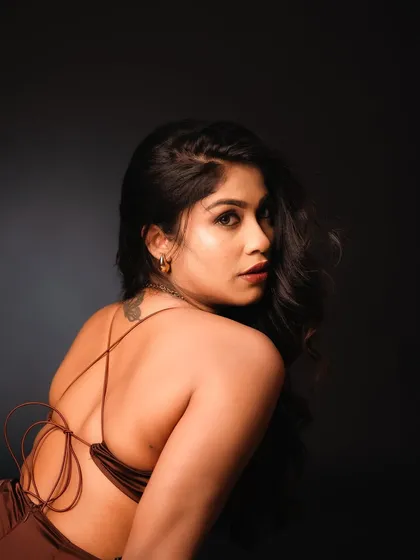 This back-profile shot in the studio highlights the elegant design of the dress and the model's pose. The dramatic lighting creates a sense of mystery and sophistication.