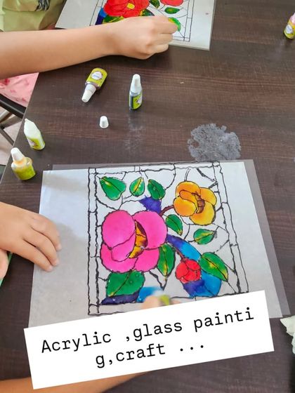 A close-up of a student working on a floral glass painting. The vibrant colors look stunning when they catch the light.
