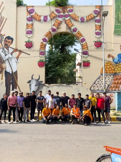 A happy group from our Nizamuddin tour, posing in front of a vibrant mural that celebrates local culture and community.