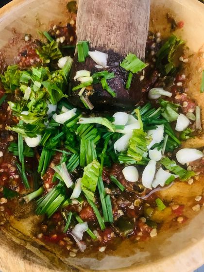 Pounding a fresh batch of chutney. I've added chopped garlic and chives on top of the pounded chilli and tomato base.