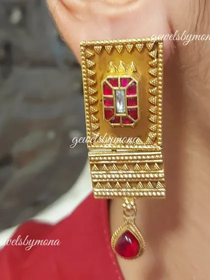 A client wearing the rectangular Dakshinaya earrings. The ruby-colored drop adds a pop of color to the intricate gold work, making them a perfect accessory for a silk saree.