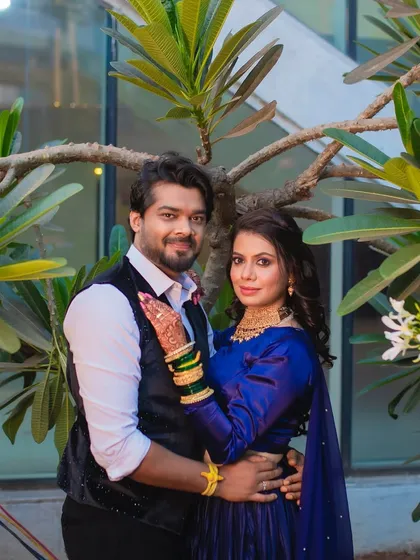A romantic couple portrait from a sangeet event. The bride's bold blue outfit is paired with a glamorous smokey eye.